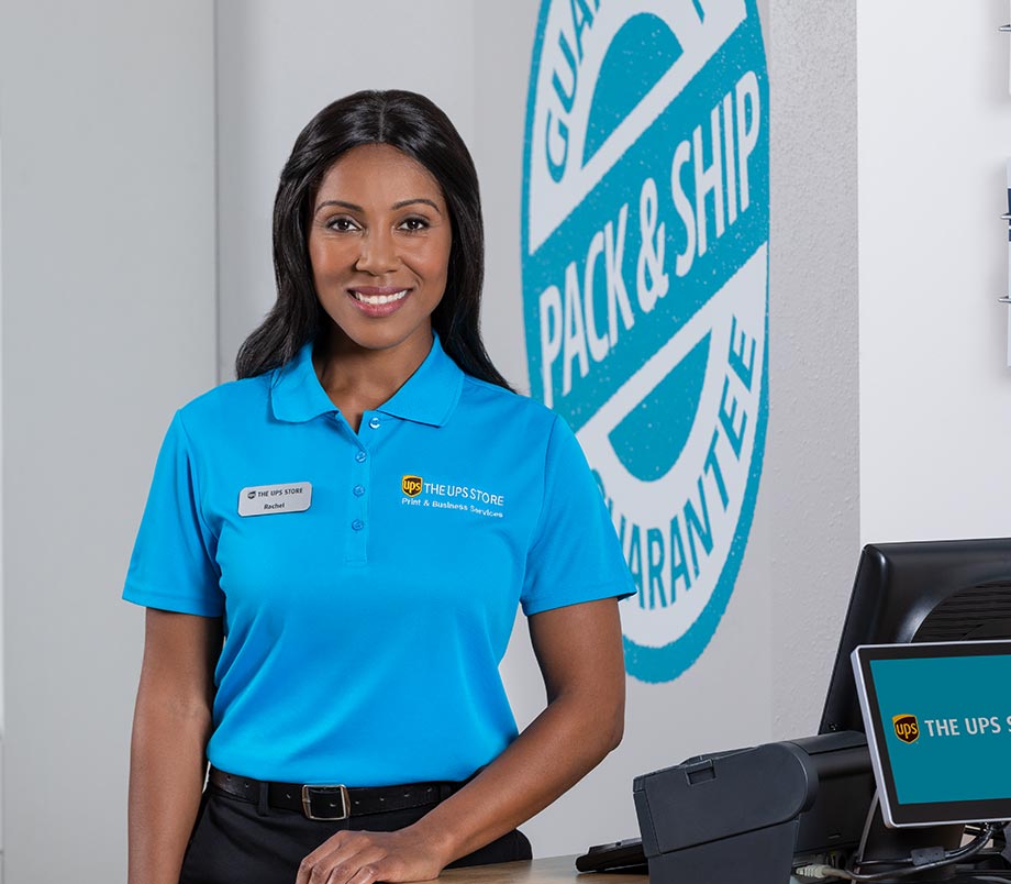 A woman smiling wearing a The UPS Store uniform